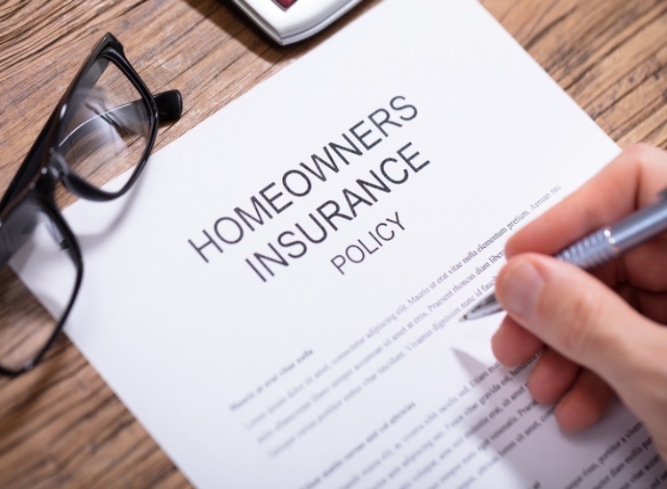 Close-up of a person signing a homeowners insurance policy document in Natick, MA